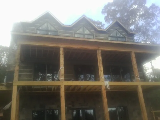 Dormers and porch framing on a large log home under construction — Roof Coating work by our crew in Niagara Falls