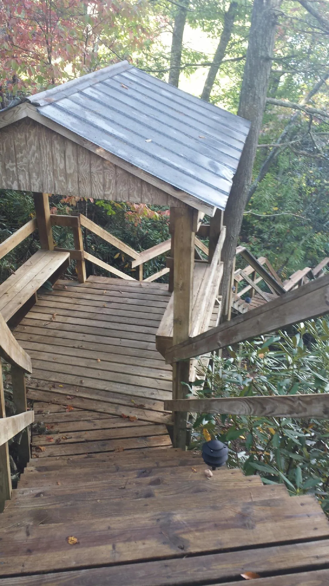 Metal roofed shelter over wooden steps on a wooded walkway — Skylight Repair & Installation work by our crew in Niagara Falls