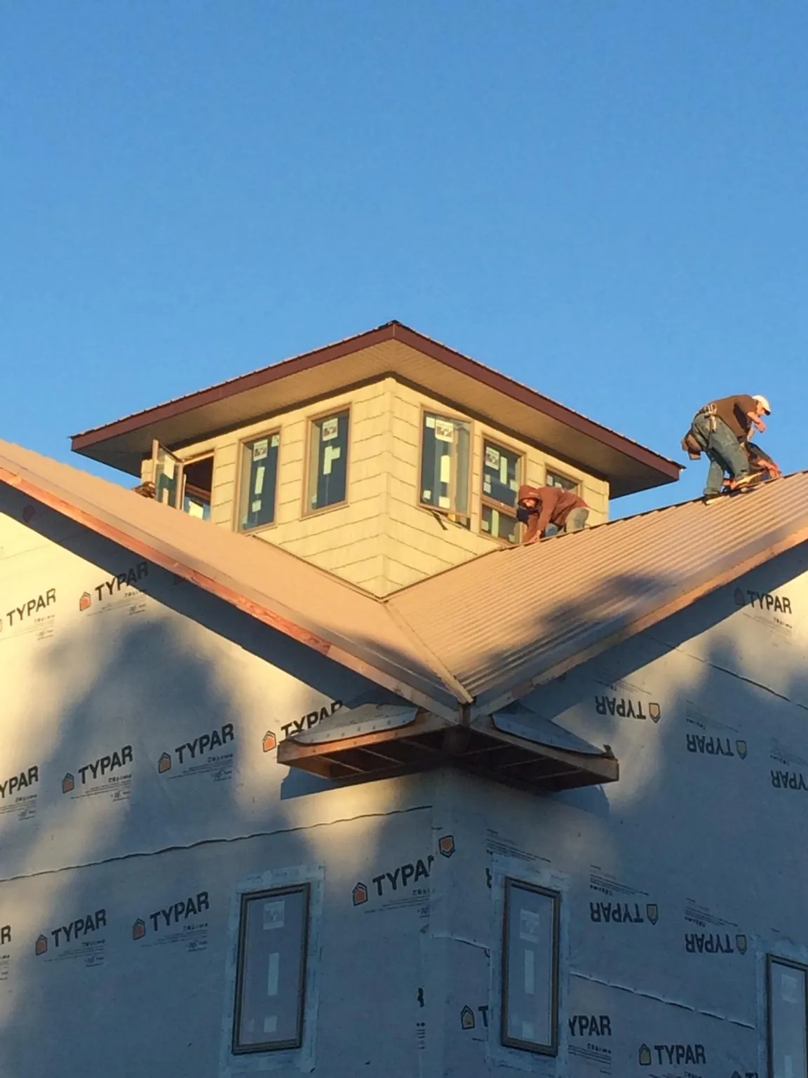 Roofers working around a rooftop cupola on a new metal roof at sunset — Roof Waterproofing in Niagara Falls by Roofing Brothers
